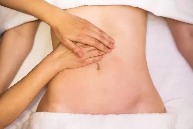 Manos de un osteópata realizando terapia manual en la zona abdominal de un paciente