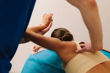 Osteópata aplicando terapia manual a una paciente deportista para mejorar bienestar y movilidad